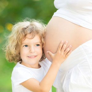 Little girl with her head on pregnant belly